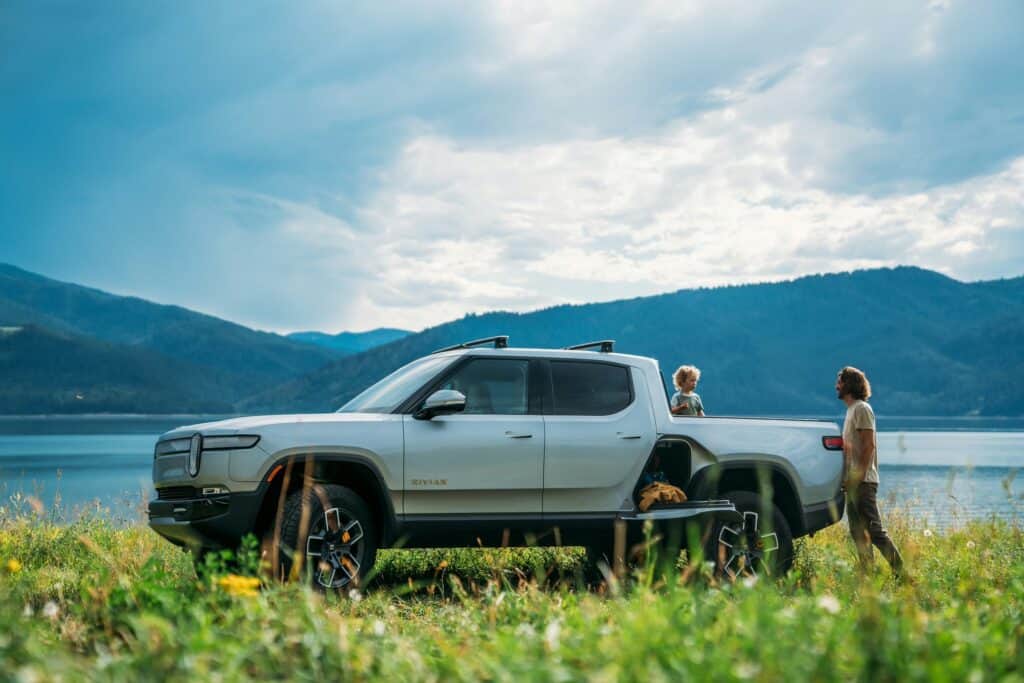 Rivian R1T with a man and child with mountains in the background